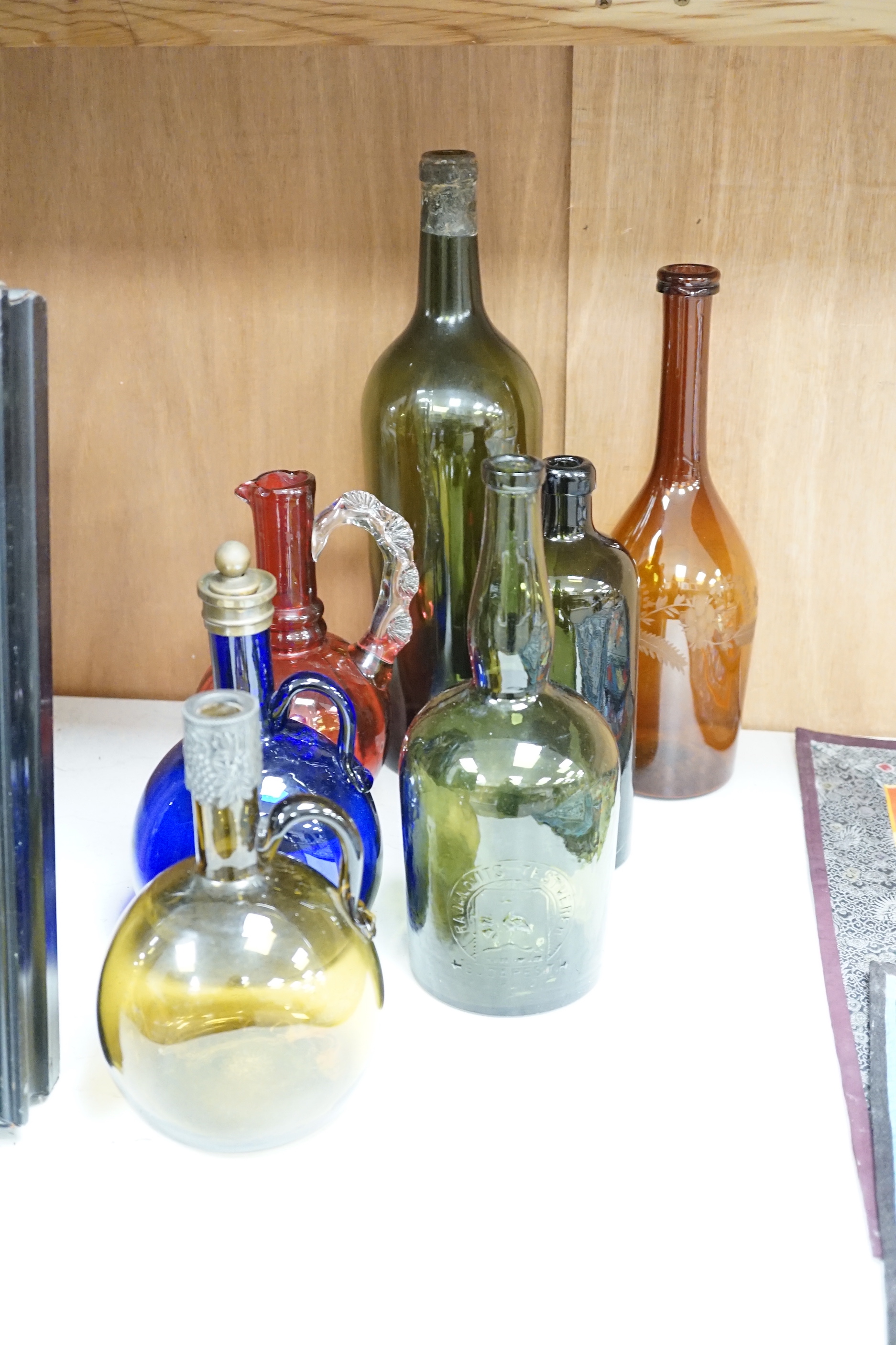 Twelve coloured glass bottles including one in the form of a violin, largest 37cm high
